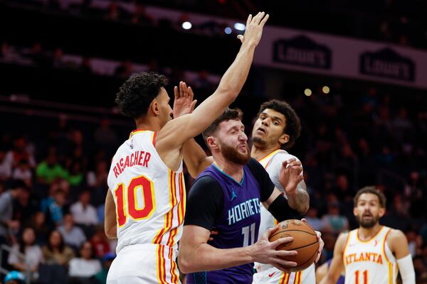 Charlotte Hornets center Jusuf Nurkic (11) fights through a double-team by Atlanta Hawks forwards Zaccharie Risacher (10) and Dominick Barlow during the first half of an NBA basketball game in Charlotte, N.C., Tuesday, March 18, 2025. (AP Photo/Nell Redmond)