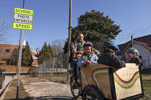 Brendan Horgan rides his bike with his children Fionnoula, 6, Bearach 4, and Ruairi’, 2, near the intersection of Metropolitan Parkway and Elbert Street in a school zone where cameras have been installed to prevent speeding on Wednesday, Jan. 31, 2024. (Natrice Miller/ Natrice.miller@ajc.com)