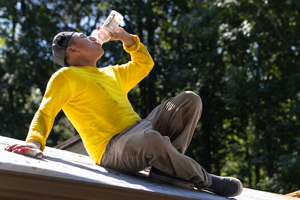 Francisco Rivera hydrates while roofing in Acworth on Wednesday.