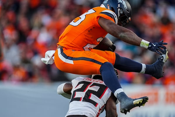 Denver Broncos running back Audric Estime (23) leaps over Atlanta Falcons cornerback Clark Phillips III (22) during the second half of an NFL football game, Sunday, Nov. 17, 2024, in Denver. (AP Photo/David Zalubowski)