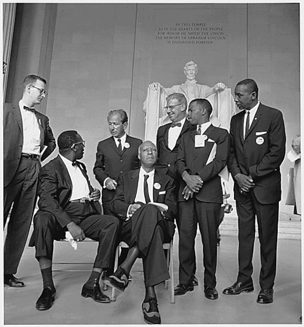 A 23-year-old John Lewis (second from the right), then chairman of the Student Nonviolent Coordinating Committee, was the youngest speaker at the March on Washington.  Others shown are from left: Mathew Ahmann, executive director of the National Catholic Conference for Interracial Justice; (seated with glasses) Cleveland Robinson, chairman of the Demonstration Committee; (beside Robinson is) A. Philip Randolph, organizer of the demonstration and veteran labor leader who helped to found the Brotherhood of Sleeping Car Porters, American Federation of Labor (AFL), and a former vice president of the American Federation of Labor and Congress of Industrial Organizations (AFL-CIO); (standing behind the two chairs) Rabbi Joachim Prinz; (wearing a bow tie and standing beside Prinz) is Joseph Rauh Jr., a Washington, D.C., attorney and civil rights, peace and union activist; and Floyd McKissick, national chairman of the Congress of Racial Equality.