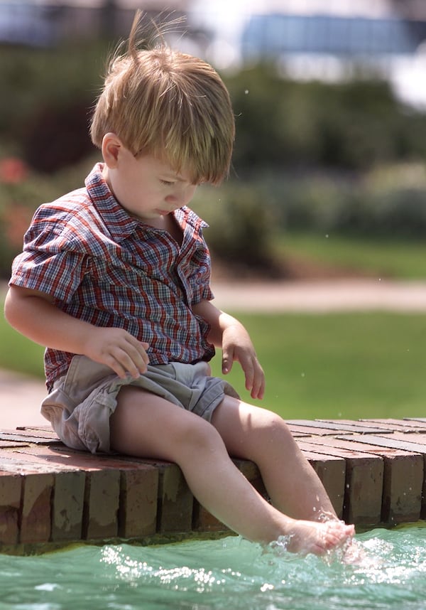 Two-year-old Zachary Mullinax cools off by splashing his feet in the fountain.