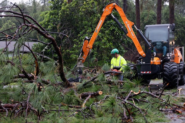 Cleanup crews work to clear storm debris, including pine trees, in a neighborhood in Valdosta.