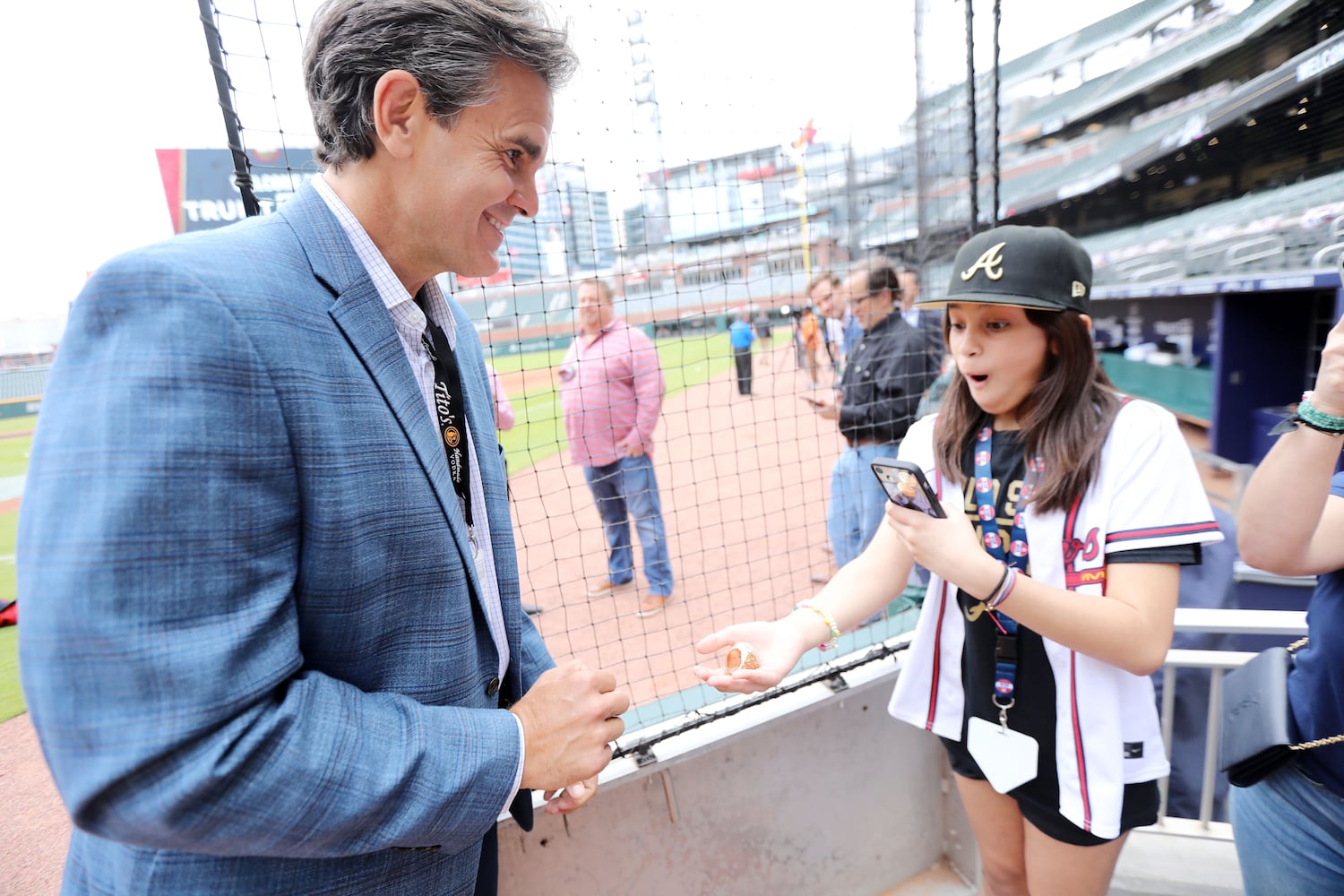 Milady Valle of New Jersey reacts as she holds the World Series ring of broadcaster Chip Caray on Monday at Truist Park. (Miguel Martinez/miguel.martinezjimenez@ajc.com)