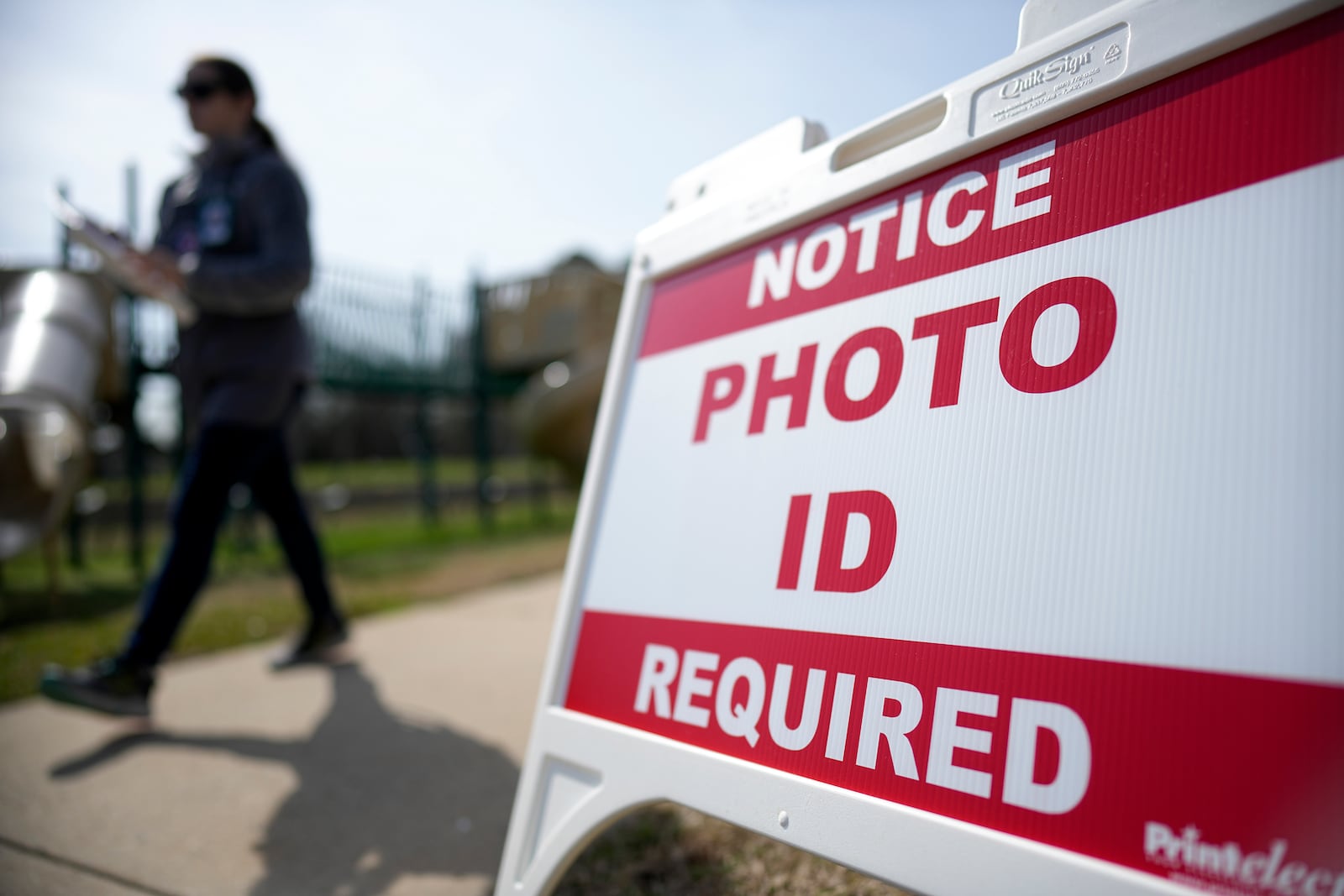 FILE - A Super Tuesday voter walks past a sign requiring a photo ID at a polling location, March 5, 2024, in Mount Holly, N.C. (AP Photo/Chris Carlson, File)