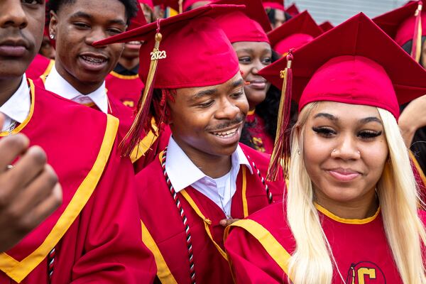 James Sims (center) smiles with other members of Creekside High School’s Tribe Academy before a group photo at their graduation ceremony at Gateway Arena in College Park on Thursday, May 18, 2023. (Arvin Temkar / arvin.temkar@ajc.com)