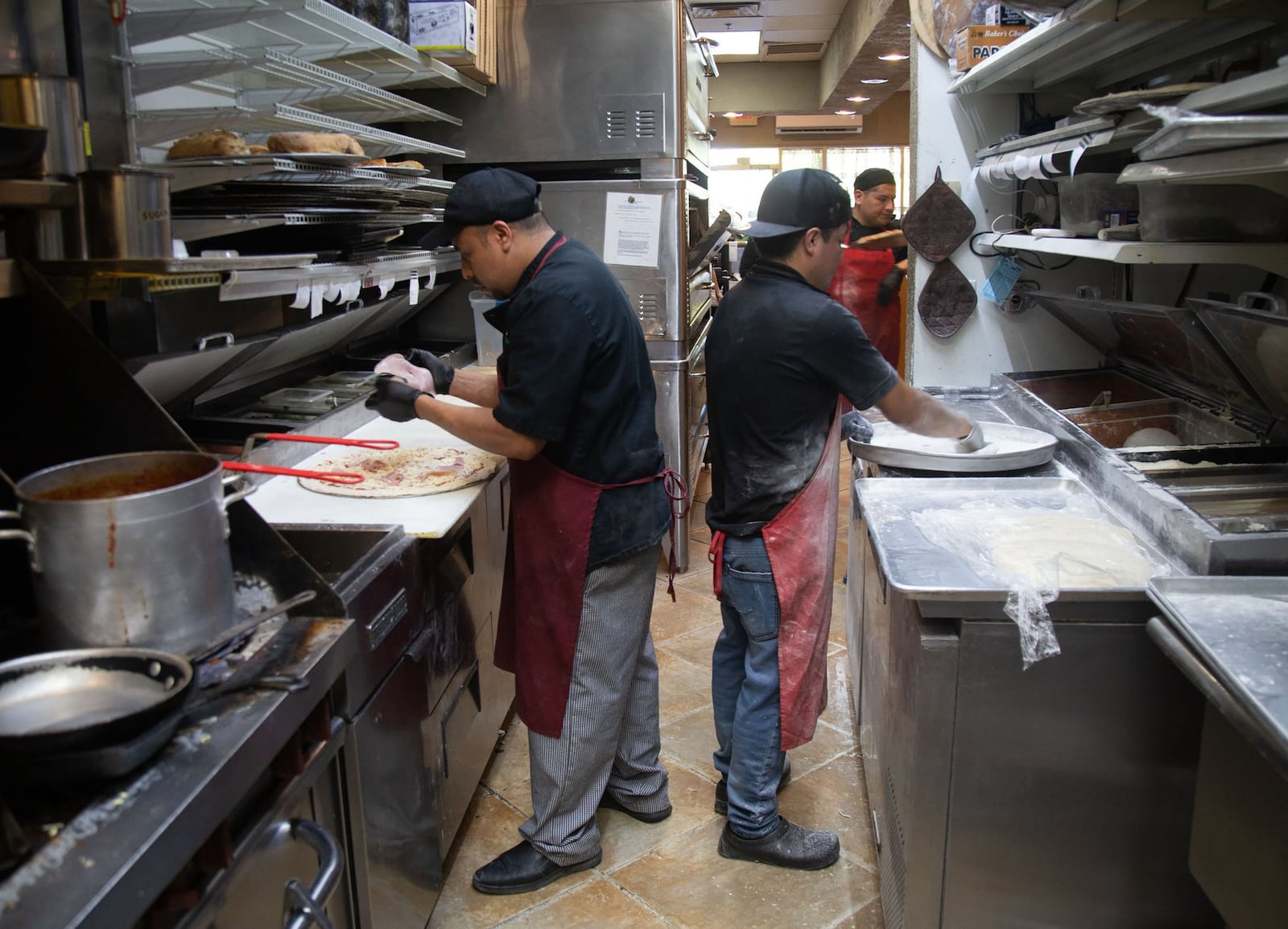 Yoni Juarez (R) and Felix Acosta (L) make pizzas during the Friday night rush at Fini’s Pizzeria in Lawrenceville. STEVE SCHAEFER / SPECIAL TO THE AJC