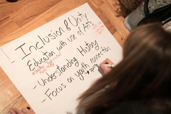 Jannine Deraney writes down her small group’s thoughts about inclusion and unity during the Healing the Racial Divide meeting at her Decatur home in late October. The meeting broke into small groups, and each group discussed a solution to their view and wrote about it on a large poster for others to see their answers. JASON GETZ / SPECIAL