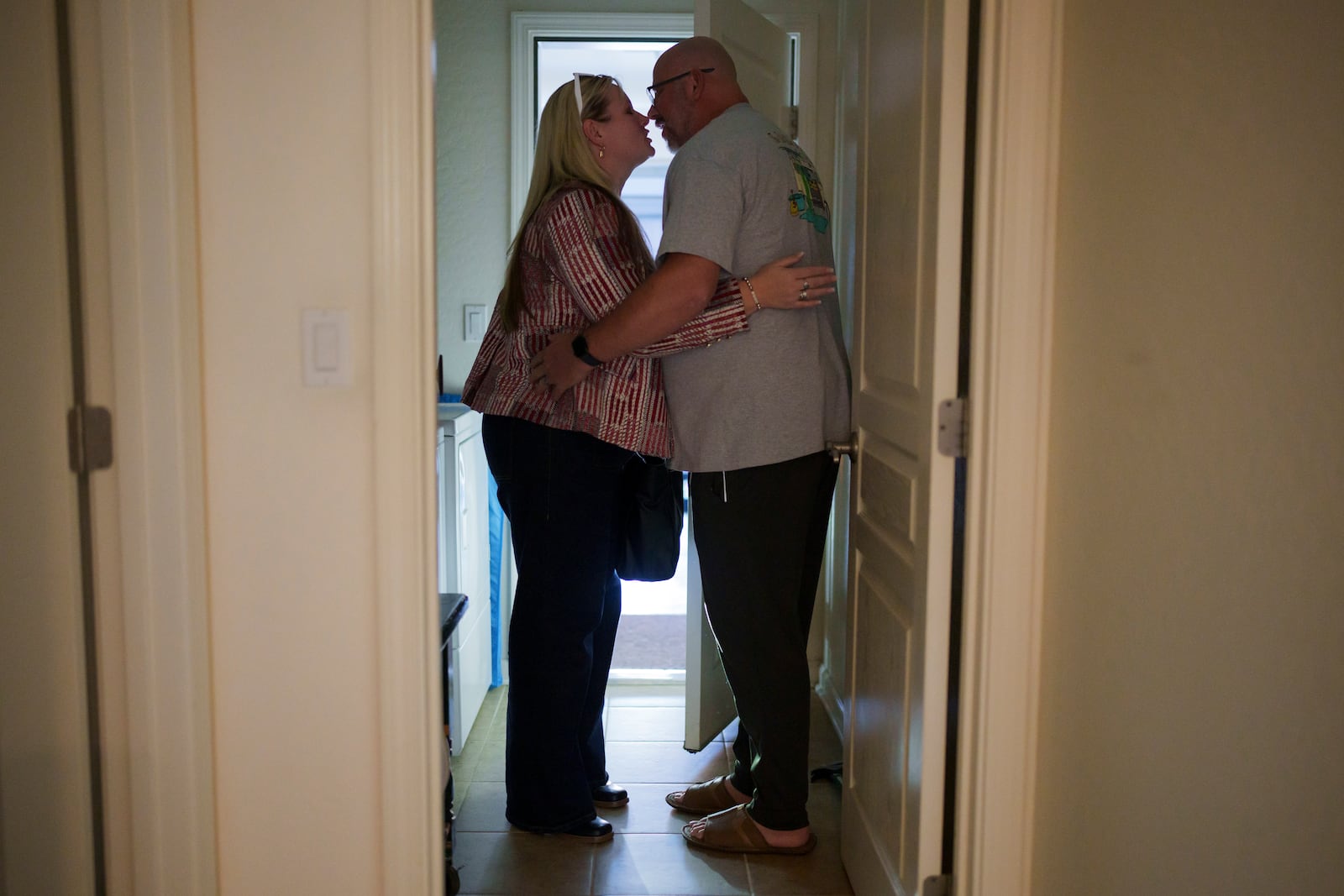 Cari-Ann Burgess, interim Registrar of Voters for Washoe County, Nev., left, kisses husband Shane Burgess as she arrives at their home Friday, Sept. 20, 2024, in Reno, Nev. (AP Photo/John Locher)