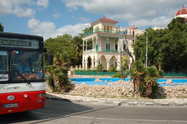 A tour bus passes a bay-front mansion in Cienfuegos, a major city in the Cuban interior. PHOTO CREDIT: Bill Osinski