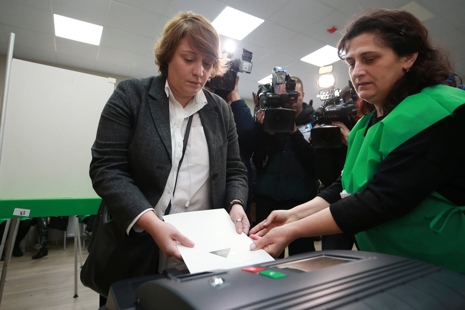 An election commission member, right, helps Elene Khoshtaria, a leader of the Coalition for Changes to casts her ballot at a polling station during the parliamentary election in Tbilisi, Georgia, Saturday, Oct. 26, 2024. (AP Photo/Zurab Tsertsvadze)