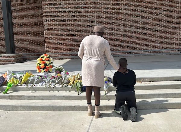 Cecil Oduory and her 10-year-old son Dylan Cheruiyot brought flowers to Jug Tavern Park to honor those killed in Wednesday's shooting.