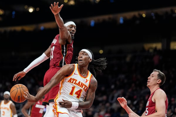 Atlanta Hawks guard Terance Mann (14) passes the ball against Miami Heat center Bam Adebayo (13) during the first half of an NBA basketball game, Monday, Feb. 24, 2025, in Atlanta. (AP Photo/Mike Stewart)