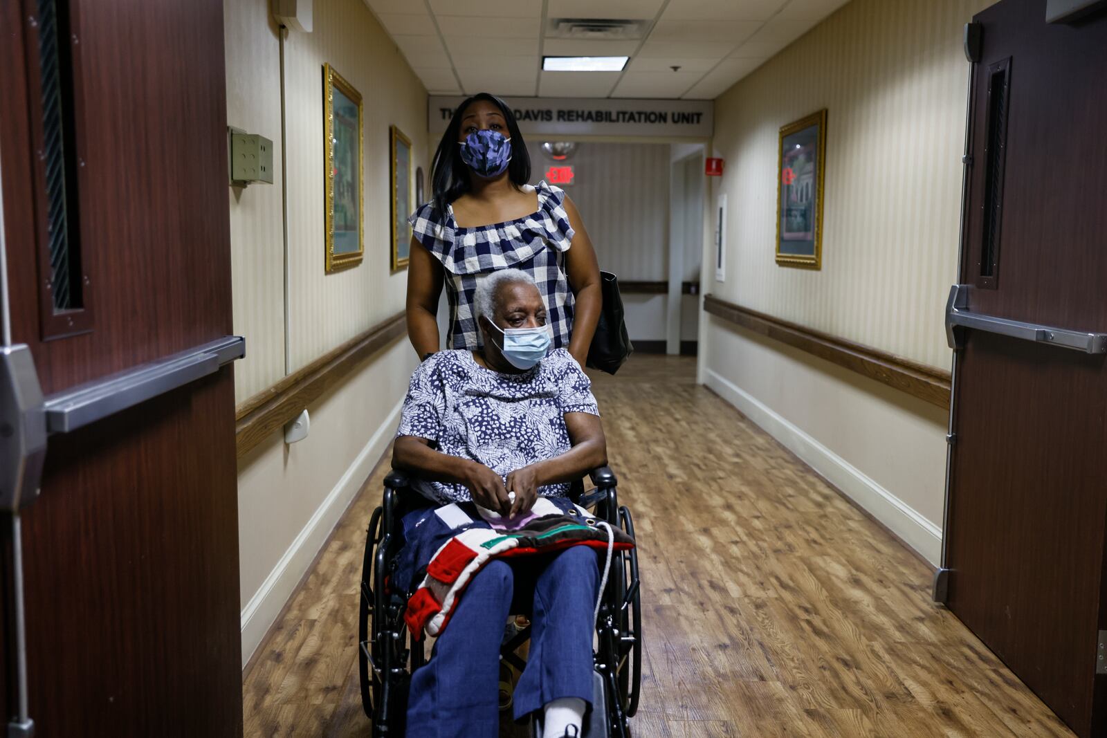 Kisha Stanley pushes her mother, Yvonne Medley, through the hallways of Sandy Springs Center for Nursing and Healing. Medley was previously a resident at Signature HealthCARE of Buckhead, where, Stanley says, showers were scant and her mother developed bed sores. (Natrice Miller / natrice.miller@ajc.com)