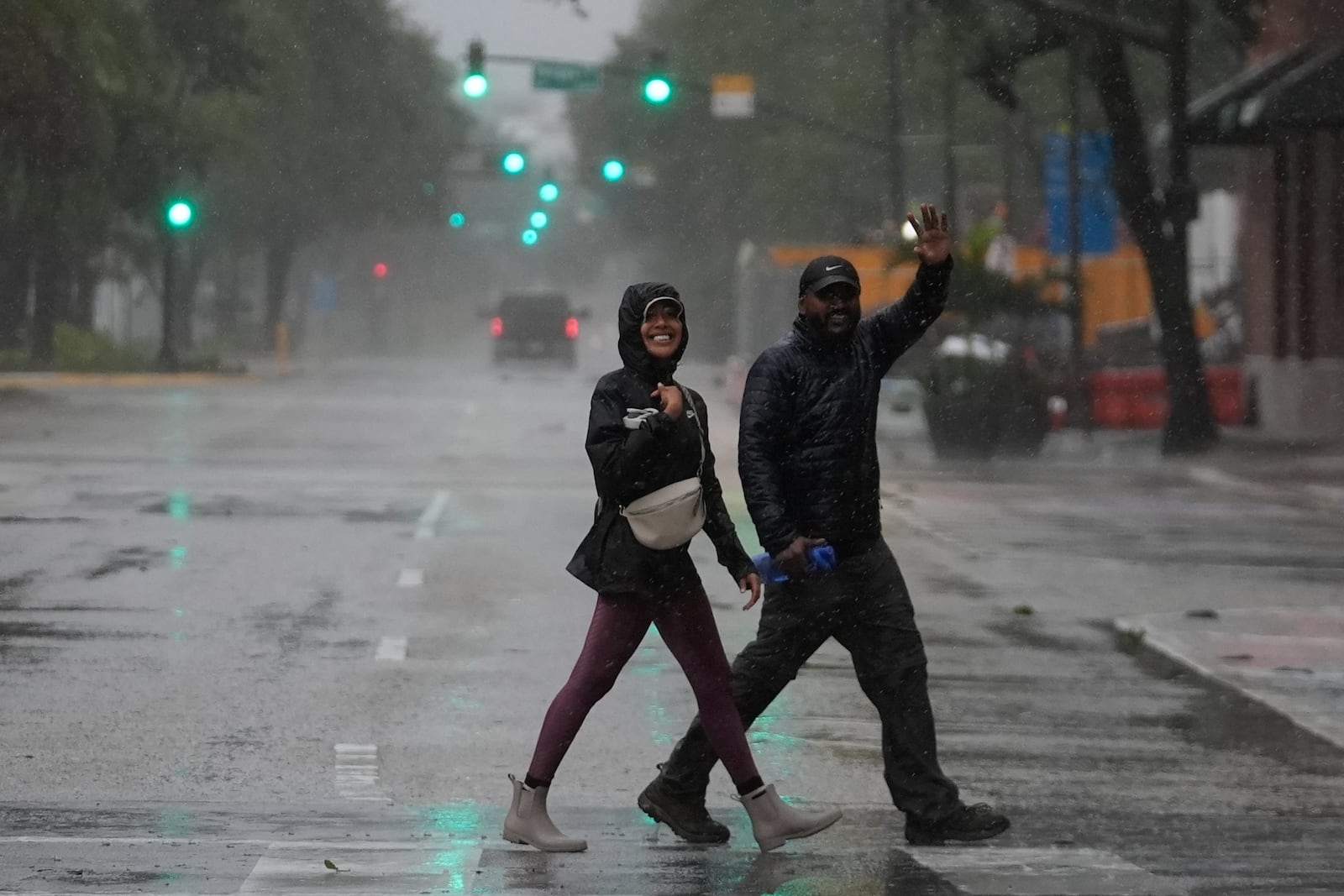 People walk through nearly-deserted downtown Tampa, Fla., in windy and rainy conditions during the approach of Hurricane Milton, Wednesday, Oct. 9, 2024. (AP Photo/Rebecca Blackwell)