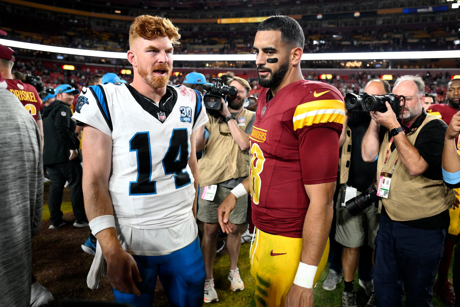 Carolina Panthers quarterback Andy Dalton (14) talks Washington Commanders quarterback Marcus Mariota (18) after an NFL football game, Sunday, Oct. 20, 2024, in Landover, Md. The Commanders 40-7. (AP Photo/Nick Wass)