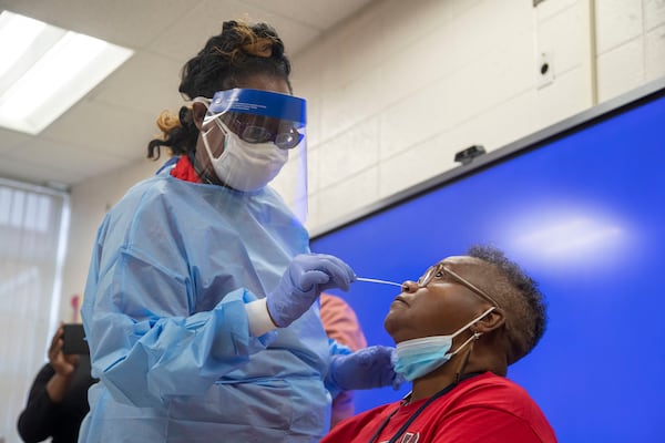 Clayton County Public Schools healthcare tech Glissa Nash takes a COVID-19 testing swab from G.P. Babb Middle School teacher Ruth Caine during a Clayton County Public Schools COVID-19 vaccination and testing drive at G.P. Babb Middle School in Forest Park on Sept. 21, 2021.  (Alyssa Pointer/AJC file photo)