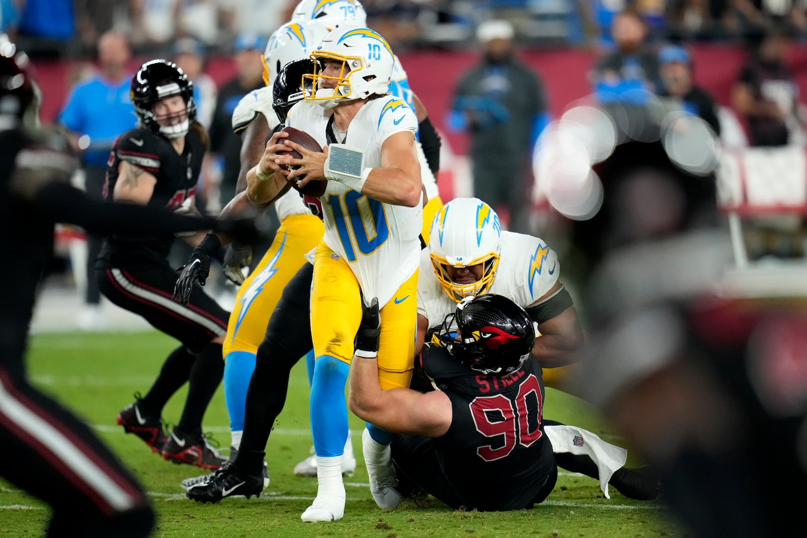 Los Angeles Chargers quarterback Justin Herbert (10) is sacked by Arizona Cardinals defensive end Ben Stille (90) during the first half of an NFL football game, Monday, Oct. 21, 2024, in Glendale Ariz. (AP Photo/Ross D. Franklin)