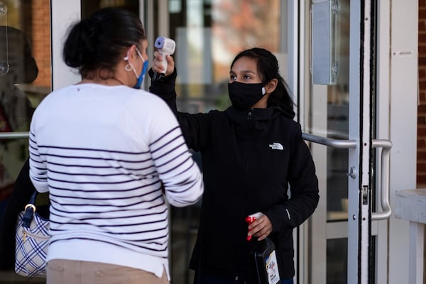 Cynthia Torrez pre-screens a patient for COVID-19 symptoms and gives her hand sanitizer before allowing her into Good Samaritan Health Center in Northwest Atlanta.  (Ben Gray for the AJC)