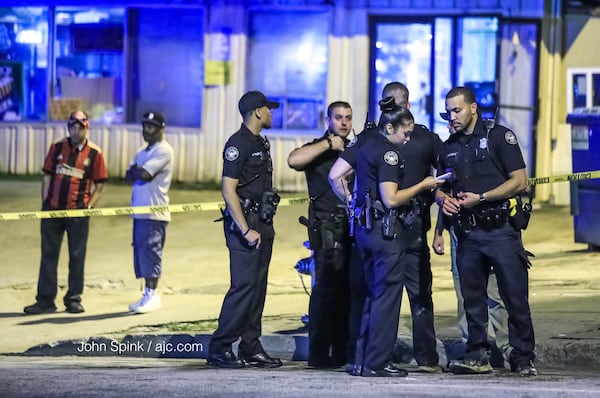 Atlanta police officers investigate a triple shooting at the Quick Pick convenience store near the Greyhound bus station on Forsyth Street. JOHN  SPINK / JSPINK@AJC.COM