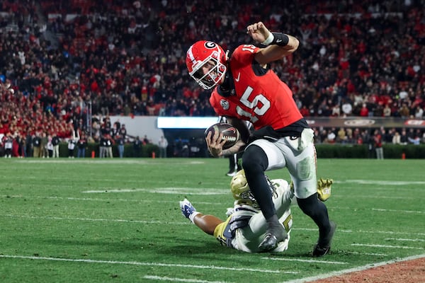 Georgia quarterback Carson Beck (15) runs for 10-yards as he is pushed out of bound by Georgia Tech defensive lineman Thomas Gore (59) during the fourth quarter at Sanford Stadium, Friday, November 29, 2024, in Athens, Ga. Georgia beat Georgia Tech 44-42 in eight overtimes.  Jason Getz / AJC)
