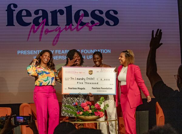 The nonprofit arm of venture capital firm Fearless Fund hosts the Fearless Moguls event at The Gathering Spot ATL on Friday, Aug 30, 2024.  Judges Jazmin Carr, left, with Shevon Jones, third from left, and Jaseña Cooper, right, award Hyacinth Tucker, second from left, the founder of The Laundry Basket LLC, a grant of $5,000 on day one of a multi-day conference which provides networking and opportunity for Black women business owners. (Jenni Girtman for The Atlanta Journal-Constitution)