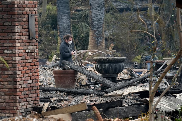 A resident sifts through their fire-damage property after the Franklin Fire swept through, Wednesday, Dec. 11, 2024, in Malibu, Calif. (AP Photo/Damian Dovarganes)