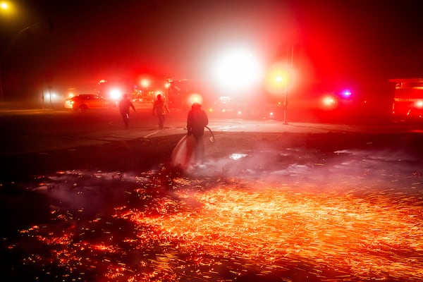 A firefighter extinguishes a brush fire as strong winds carry embers in the Winchester community of unincorporated Riverside County, Calif., on Monday, Jan. 20, 2025. (AP Photo/Noah Berger)