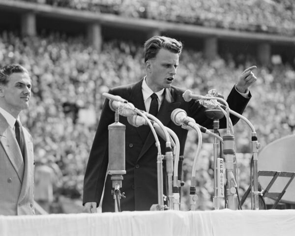 In this June 27, 1954, file photo, evangelist Billy Graham speaks to over 100,000 Berliners at the Olympic Stadium in Berlin, Germany. Graham, who transformed American religious life through his preaching and activism, becoming a counselor to presidents and the most widely heard Christian evangelist in history, has died. AP PHOTO, FILE