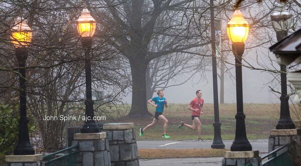 Joggers make their way through the fog in Piedmont Park on Friday morning. Metro Atlanta was under a dense fog advisory. JOHN SPINK / JSPINK@AJC.COM