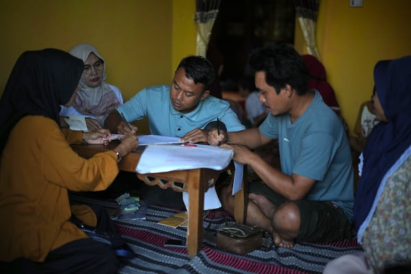 Members of a cocoa farmers' cooperative book their savings during a gathering in Tanjung Rejo, Lampung province, Indonesia, Wednesday, Feb. 19, 2025. (AP Photo/Dita Alangkara)