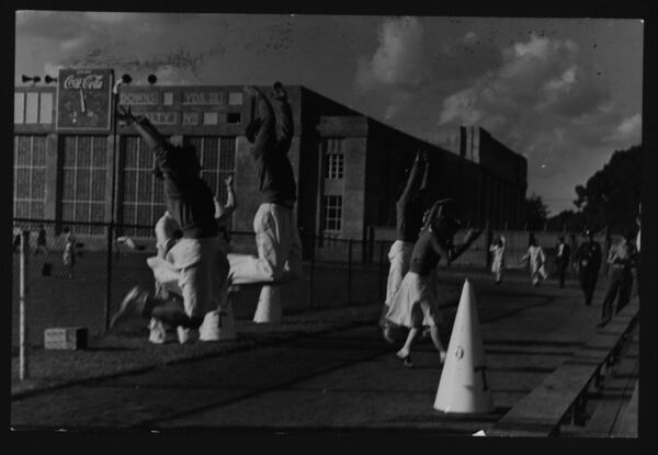 Georgia Tech cheerleaders lead on cheer with old gymnasium in background.