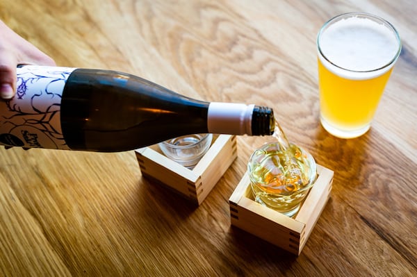 The sake overflow pour at Salaryman flanked by a Three Taverns Ukiyo Japanese Rice Lager. CONTRIBUTED BY HENRI HOLLIS