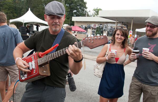 Gary O'Bryan of Atlanta tries a few licks on one of the Bohemian Guitars, made from old oil and gasoline cans, during his visit to the East Atlanta Village Strut Festival.