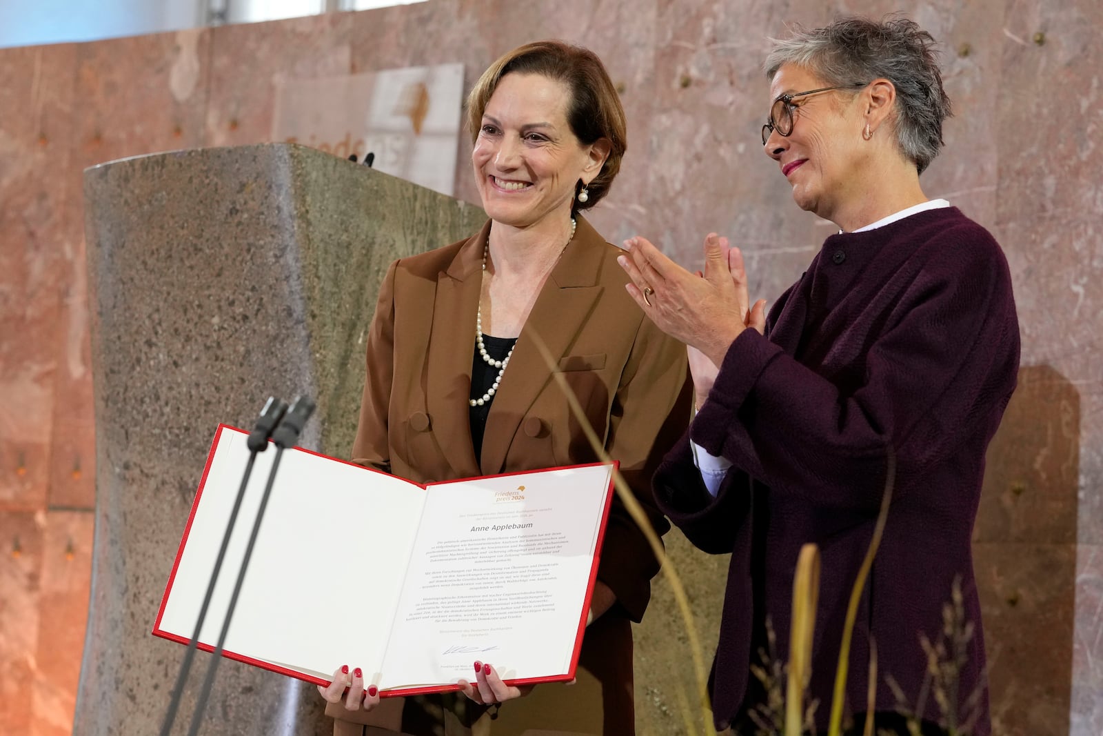 American journalist and historian Anne Applebaum, left, is awarded with the Peace Prize of the German Book Trade by Karin Schmidt-Friderichs, head of the German Publishers and Booksellers Association during a ceremony at the St. Paul's Church in Frankfurt, Germany, Sunday, Oct. 20, 2024.(AP Photo/Martin Meissner, Pool)