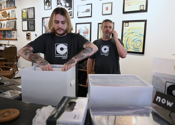 Connor Herrington (right) talks on the phone as Luke Brown prepares for a curbside delivery at Comeback Vinyl on Friday, May 8, 2020. (Hyosub Shin / Hyosub.Shin@ajc.com)