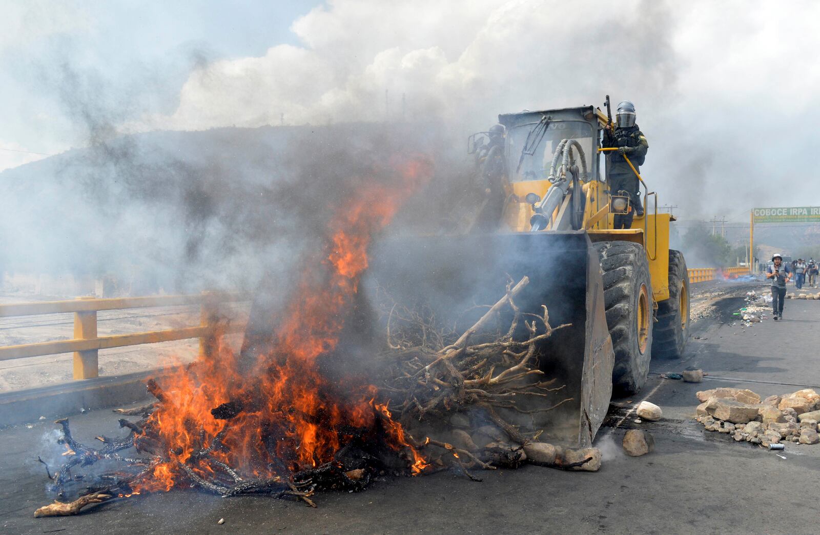 Police clears the fire barricades with a tractor as supporters of former Bolivian President Evo Morales block roads to pressure against him being prosecuted over allegations of minor abuse, near Cochabamba, Bolivia, Friday, Oct. 25, 2024. (AP Photo/Daniel Cartagena)