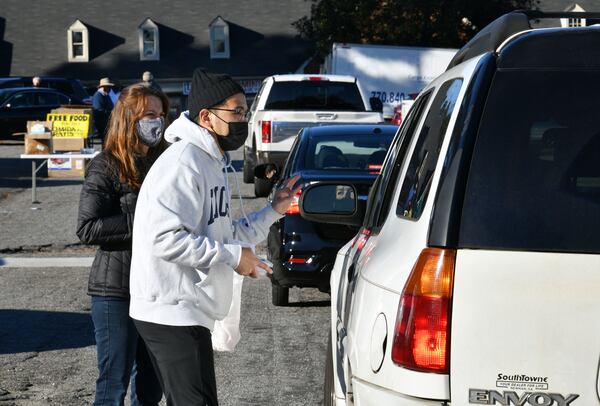 January 29, 2021 Norcross - Woojin Kang and Vicki Tyler (left), volunteers from The Nett Church, assist clients, who line up to pick up meals and essential items that Chef Hank Reid and volunteers prepared, at the parking lot of The Nett Church in Norcross on Friday, January 29, 2021. Hank Reid has been driving a food truck to carry meals where they're needed in Gwinnett County. (Hyosub Shin / Hyosub.Shin@ajc.com)