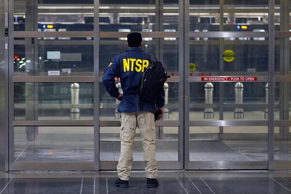 A member of the National Transportation Safety Board (NTSB) stands by a door at Ronald Reagan Washington National Airport, Wednesday, Jan. 29, 2025, in Arlington, Va. (AP Photo/Julio Cortez)