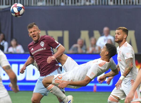 Atlanta United defender Miles Robinson (12) attempts a scissor kick against Colorado Rapids forward Diego Rubio (7) during the first half in a MLS soccer match at Mercedes-Benz Stadium in Atlanta on Saturday, April 27, 2019. HYOSUB SHIN / HSHIN@AJC.COM