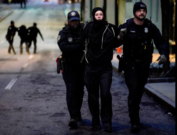 Apparent Forest Defenders protesters are arrested during a rally in which a police car was set afire in Atlanta on Saturday, Jan 21, 2023. (Ben Hendren for The Atlanta Journal-Constitution)