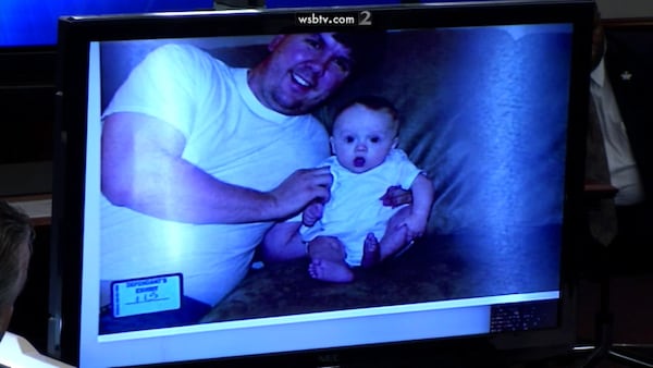 Justin Ross Harris holds baby Cooper in this family photo that Harris' defense team shows the court during questioning of Harris' ex-wife Leanna Taylor, during Harris' murder trial at the Glynn County Courthouse in Brunswick, Ga., on Monday, Oct. 31, 2016. (screen capture via WSB-TV)