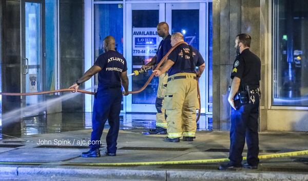 Investigators clean a crime scene in front of a building in the 800 block of Peachtree Street in Midtown, where a man was found beaten to death Wednesday morning. JOHN SPINK / JSPINK@AJC.COM