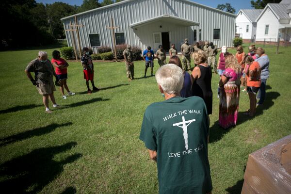 SUMMERTOWN, GA - JULY 14, 2020: Summertown Food Pantry volunteer Paul Pierre leads a group in prayer, blessing the food they are about to give to the 116 people lined up in their cars. (AJC Photo/Stephen B. Morton)