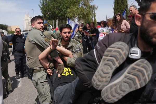 Israeli servicemen remove people as they block a road for the Israeli parliament during an anti-government protest after the Israeli cabinet passed a no-confidence vote against the country's attorney general, taking a first step toward her dismissal, in Jerusalem, Tuesday, March 25, 2025. (AP Photo/Ohad Zwigenberg)