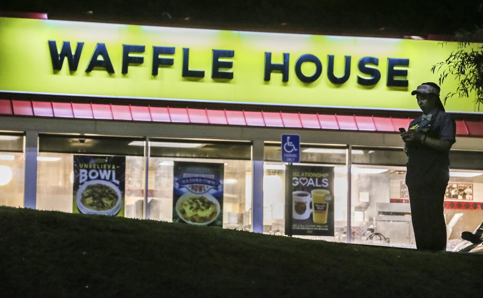 A woman was shot and killed on June 13, 2017, outside a DeKalb County Waffle House in front of multiple people. Here, in the aftermath of the killing, a Waffle House employee stands in the parking lot. JOHN SPINK/JSPINK@AJC.COM.