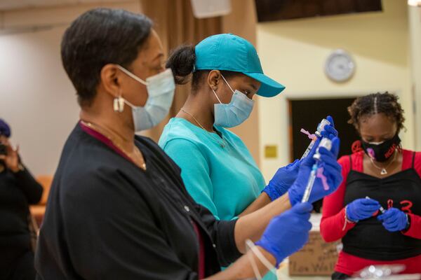 Registered nurses Ashanit Booker, center, and Arnita Dunwell prepare the COVID-19 vaccine shot during a vaccination event put on by the DeKalb County Board of Health and Delta Sigma Theta Sorority Inc. (Alyssa Pointer / Alyssa.Pointer@ajc.com)