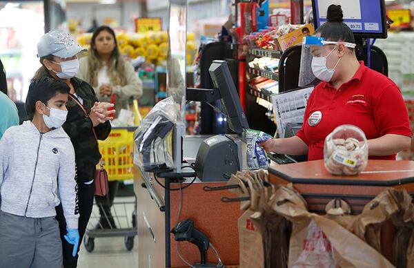 Amid concerns of the spread of COVID-19, a checker rings up items for shoppers Monday at El Rancho grocery store in Dallas.