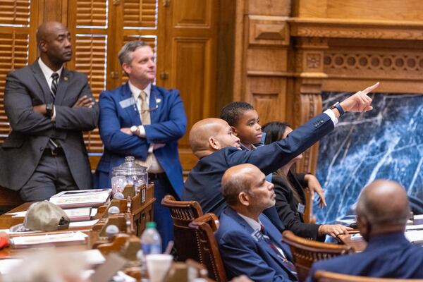 State Sen. Jason Esteves, D-Atlanta, shows his son Jaeden the voting board following a vote Tuesday during a special legislative session for redistricting at the Georgia Capitol. (Arvin Temkar / arvin.temkar@ajc.com)