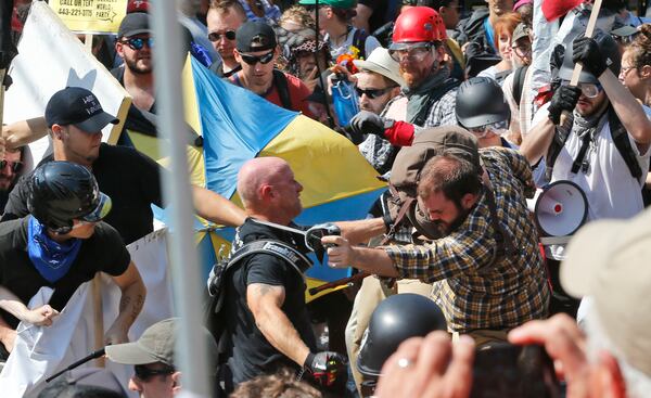 White nationalist demonstrators clash with counter demonstrators at the entrance to Lee Park in Charlottesville, Va., Saturday, Aug. 12, 2017.  Gov. Terry McAuliffe declared a state of emergency and police dressed in riot gear ordered people to disperse after chaotic violent clashes between white nationalists and counter protestors.  (AP Photo/Steve Helber)